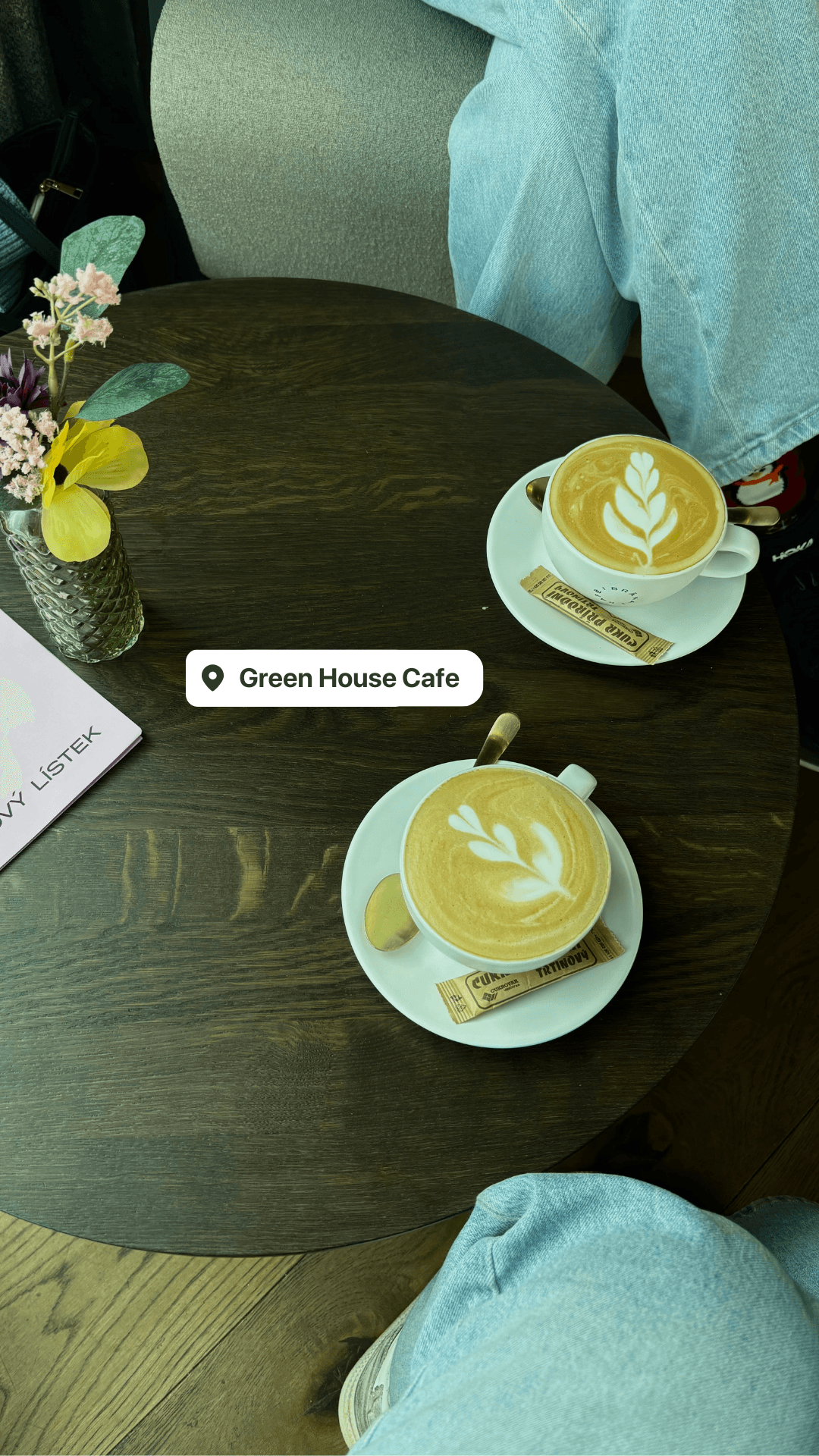 Two lattes with leaf art on a dark wooden table at Green House Cafe